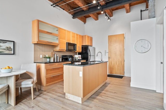 150 E Main St Unit 512, Columbus, OH 43215 - kitchen with black appliances, a towering ceiling, an island with sink, backsplash, and beamed ceiling