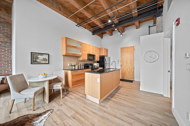 150 E Main St Unit 512, Columbus, OH 43215 - kitchen with black appliances, a high ceiling, an island with sink, light wood-style floors, and dark countertops