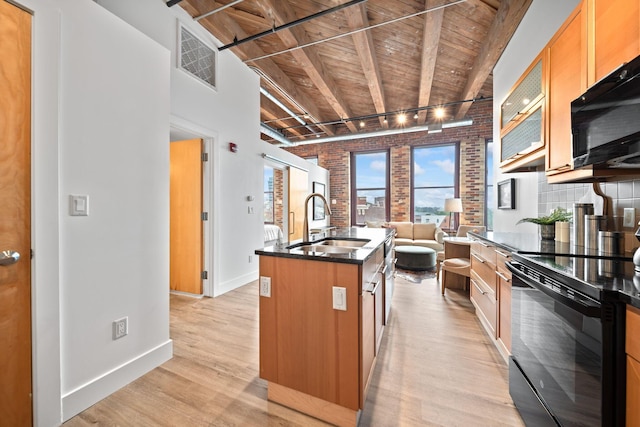 150 E Main St Unit 512, Columbus, OH 43215 - kitchen featuring black appliances, brick wall, a wooden ceiling with exposed beams, open floor plan, and light wood-type flooring