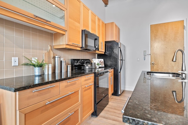 150 E Main St Unit 512, Columbus, OH 43215 - kitchen with black appliances, light wood-type flooring, decorative backsplash, and dark stone counters