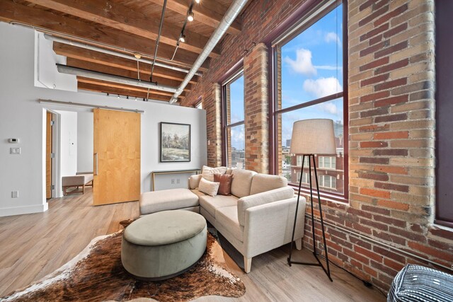 150 E Main St Unit 512, Columbus, OH 43215 - living room featuring light wood-style flooring, brick wall, and a wood ceiling with exposed beams