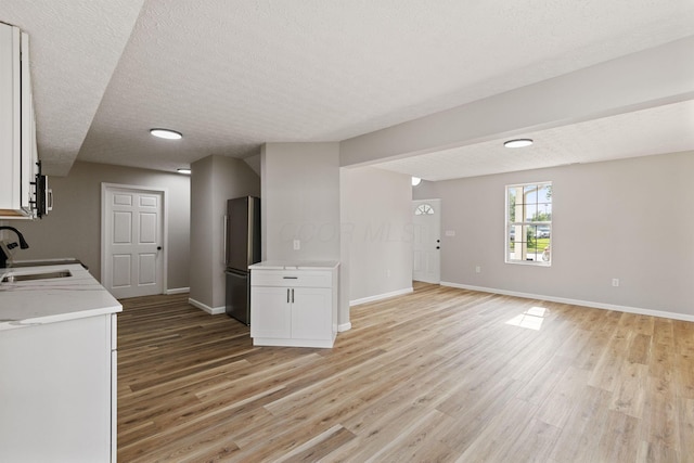 1664 S Champion Ave, Columbus, OH 43207 - kitchen featuring freestanding refrigerator, light wood-style floors, light countertops, a textured ceiling, and white cabinets