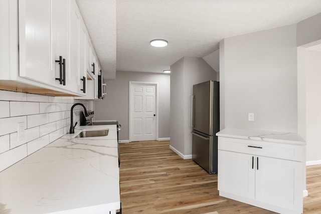 1664 S Champion Ave, Columbus, OH 43207 - kitchen with freestanding refrigerator, light wood-style floors, white cabinets, tasteful backsplash, and light stone countertops