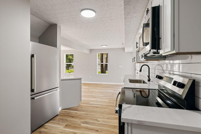 1664 S Champion Ave, Columbus, OH 43207 - kitchen featuring appliances with stainless steel finishes, a textured ceiling, light wood-style floors, and backsplash