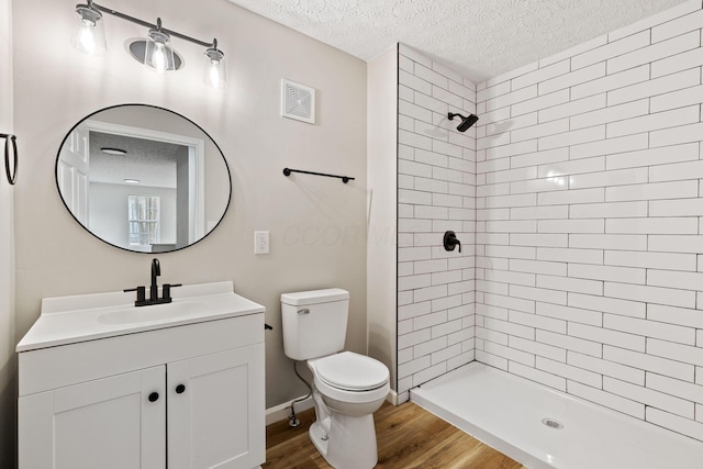 1664 S Champion Ave, Columbus, OH 43207 - full bathroom featuring a textured ceiling, tiled shower, vanity, and wood finished floors