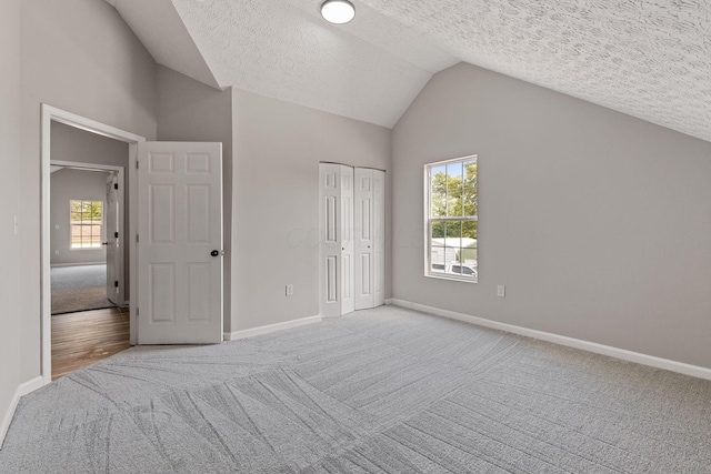 1664 S Champion Ave, Columbus, OH 43207 - unfurnished bedroom with carpet, vaulted ceiling, a textured ceiling, multiple windows, and a closet