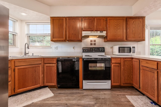 3351 Lindstrom Dr, Columbus, OH 43228 - kitchen featuring white microwave, black dishwasher, range with electric stovetop, under cabinet range hood, and wood finished floors