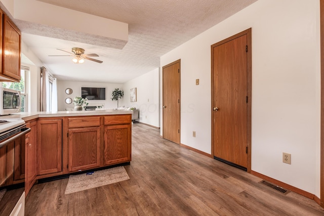3351 Lindstrom Dr, Columbus, OH 43228 - kitchen featuring electric range, a peninsula, stainless steel microwave, wood finished floors, and ceiling fan