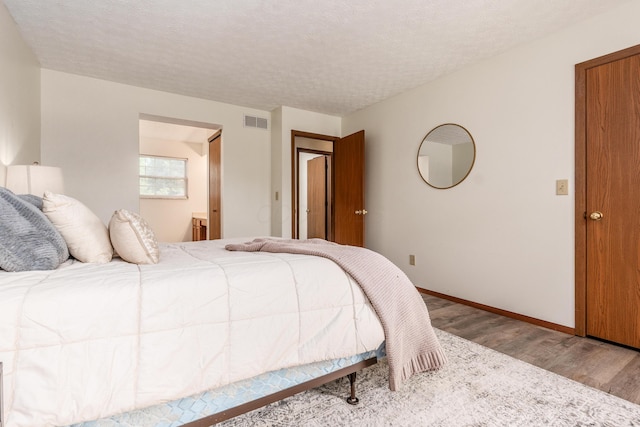 3351 Lindstrom Dr, Columbus, OH 43228 - bedroom with wood finished floors, connected bathroom, and a textured ceiling