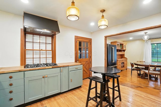 2620 Edgevale Rd, Columbus, OH 43221 - kitchen with butcher block counters, appliances with stainless steel finishes, wall chimney exhaust hood, light wood-style flooring, and decorative light fixtures