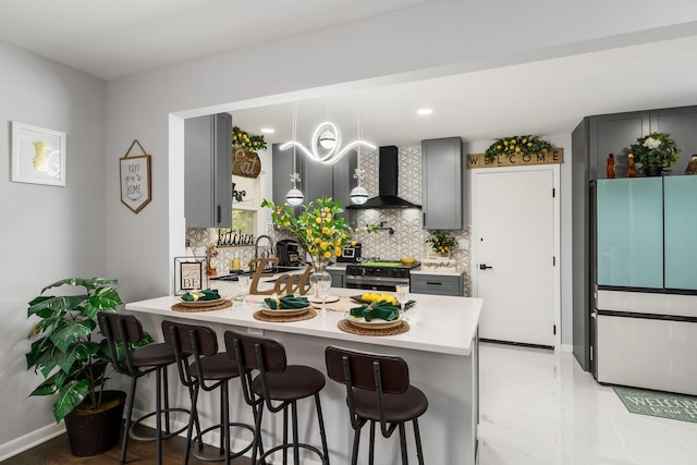 1174 Belden Rd, Columbus, OH 43229 - kitchen with wall chimney exhaust hood, freestanding refrigerator, gray cabinets, a peninsula, and backsplash