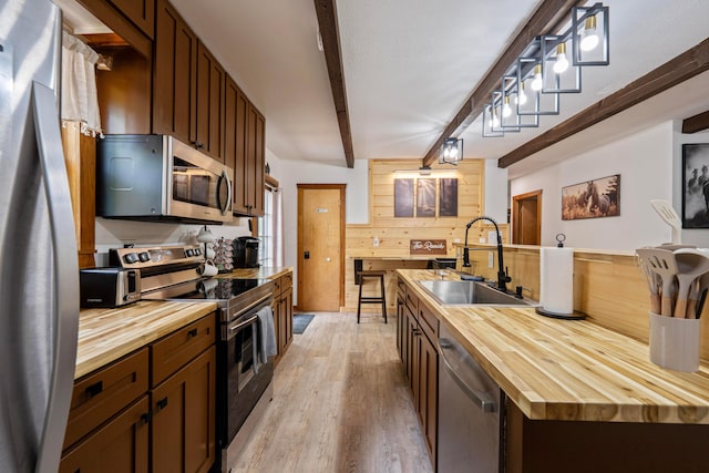 63775 State Route 56, Creola, OH 45622 - kitchen featuring wood counters, appliances with stainless steel finishes, beamed ceiling, light wood-style floors, and wooden walls