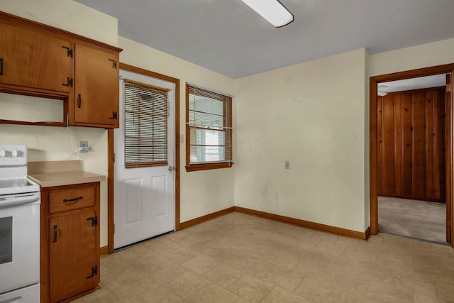 824 Colonial Dr, Heath, OH 43056 - kitchen featuring white range with electric stovetop, light floors, light countertops, brown cabinets, and wood walls