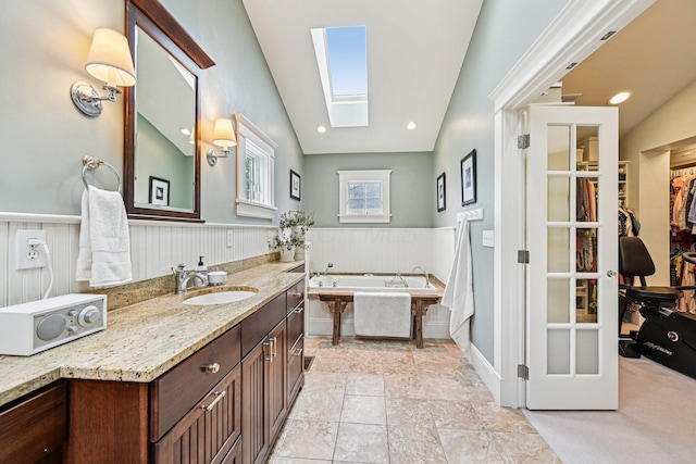 1968 Coventry Rd, Upper Arlington, OH 43212 - bathroom featuring a garden tub, vanity, a skylight, a wainscoted wall, and lofted ceiling