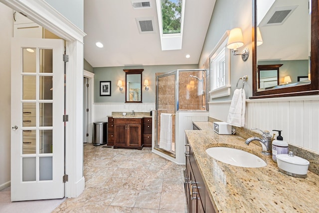 1968 Coventry Rd, Upper Arlington, OH 43212 - full bathroom featuring a stall shower, a skylight, lofted ceiling, a wainscoted wall, and two vanities