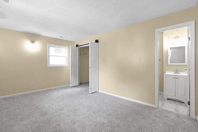 1086 S Hampton Rd, Columbus, OH 43227 - unfurnished bedroom featuring light carpet, a textured ceiling, ensuite bath, a barn door, and a closet
