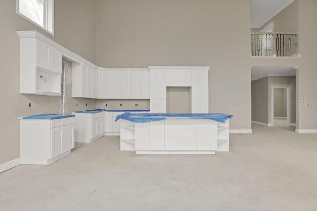 3699 Kassidy Dr, Grove City, OH 43123 - kitchen featuring open shelves, a high ceiling, light colored carpet, white cabinetry, and a kitchen island
