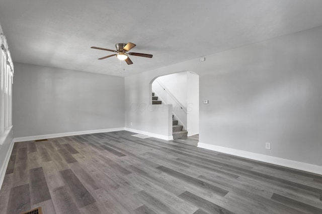 794 E Deshler Ave, Columbus, OH 43206 - empty room featuring ceiling fan, arched walkways, dark wood finished floors, and stairs