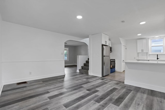 794 E Deshler Ave, Columbus, OH 43206 - kitchen with freestanding refrigerator, arched walkways, stove, light countertops, and white cabinets