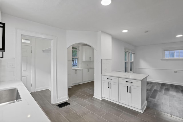 794 E Deshler Ave, Columbus, OH 43206 - kitchen featuring white cabinetry, arched walkways, backsplash, recessed lighting, and a peninsula
