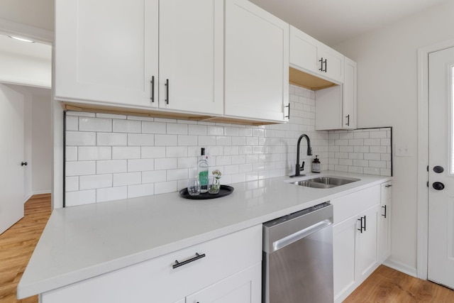 2203 Belcher Dr, Columbus, OH 43224 - kitchen with stainless steel dishwasher, backsplash, light countertops, light wood-style flooring, and white cabinets