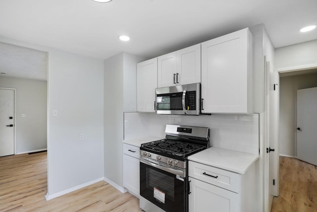 1358 Moler Rd, Columbus, OH 43207 - kitchen with appliances with stainless steel finishes, light wood-type flooring, decorative backsplash, white cabinetry, and recessed lighting
