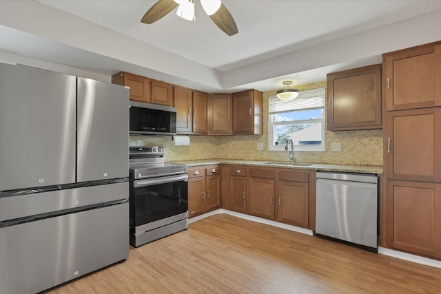 1698 Woodcrest Rd, Columbus, OH 43232 - kitchen with appliances with stainless steel finishes, light wood finished floors, decorative backsplash, and brown cabinets
