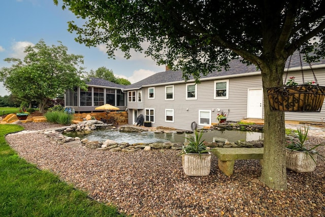 1163 Sitterley Rd NW, Canal Winchester, OH 43110 - back of property featuring a sunroom, a garden pond, a patio area, roof with shingles, and a chimney