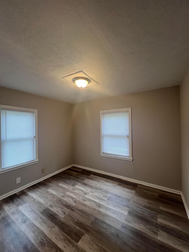 2769 Mcguffey Rd, Columbus, OH 43211 - unfurnished room featuring a textured ceiling, healthy amount of natural light, and dark wood-style flooring