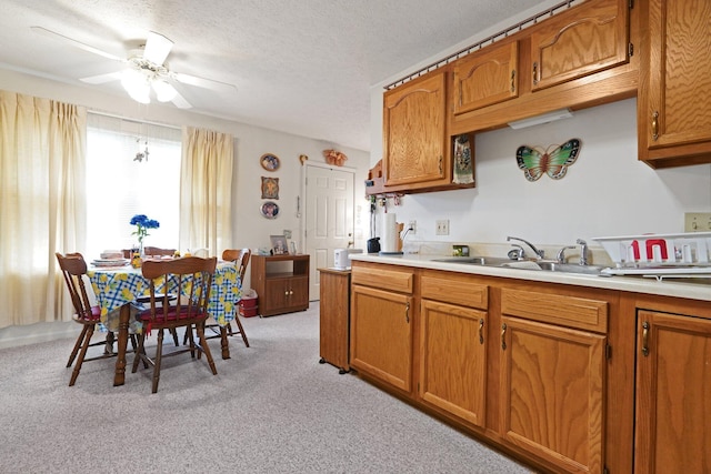 1138 Ohio Ave, Logan, OH 43138 - kitchen with light countertops, light colored carpet, ceiling fan, brown cabinets, and a textured ceiling