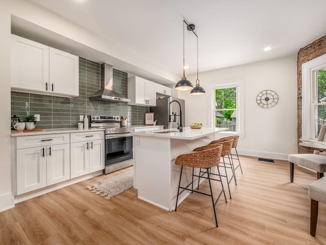 935 S Ohio Ave, Columbus, OH 43206 - kitchen with stainless steel appliances, wall chimney range hood, plenty of natural light, light countertops, and recessed lighting