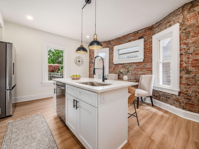 935 S Ohio Ave, Columbus, OH 43206 - kitchen featuring appliances with stainless steel finishes, light wood-type flooring, white cabinets, decorative light fixtures, and a center island with sink