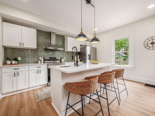935 S Ohio Ave, Columbus, OH 43206 - kitchen featuring wall chimney exhaust hood, stainless steel appliances, light wood-type flooring, decorative backsplash, and recessed lighting