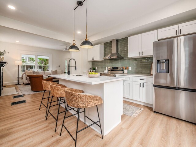 935 S Ohio Ave, Columbus, OH 43206 - kitchen with stainless steel appliances, wall chimney range hood, light wood-style floors, light countertops, and recessed lighting