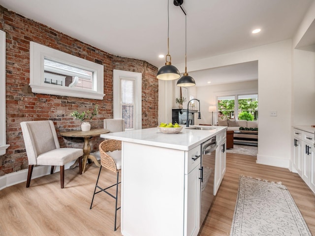 935 S Ohio Ave, Columbus, OH 43206 - kitchen with light wood-style flooring, dishwasher, white cabinetry, brick wall, and light countertops
