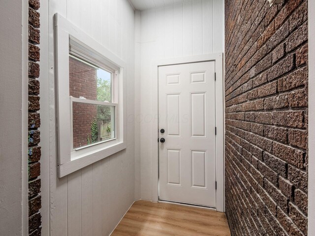 935 S Ohio Ave, Columbus, OH 43206 - doorway to outside featuring light wood finished floors, wood walls, and brick wall