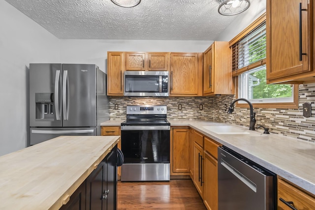 5528 Westerville Crossing Dr, Westerville, OH 43081 - kitchen with stainless steel appliances, a textured ceiling, dark wood finished floors, backsplash, and brown cabinetry