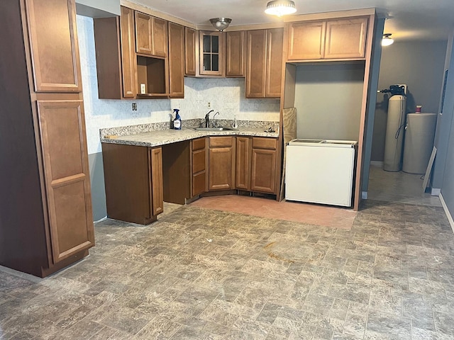 4345 Lancaster Kirkersville Rd NW, Lancaster, OH 43130 - kitchen with brown cabinetry, decorative backsplash, glass insert cabinets, washer / clothes dryer, and light stone counters