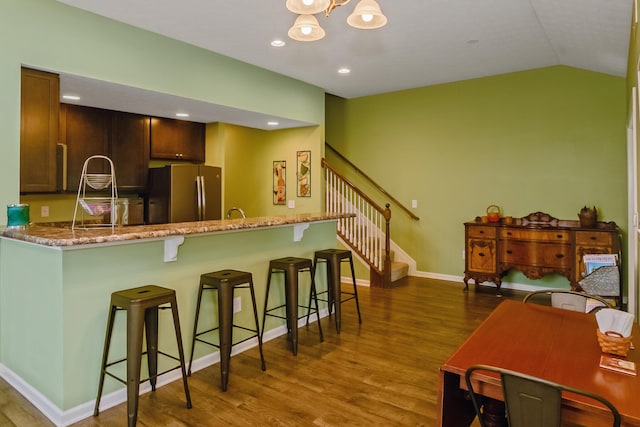3242 Rossmore Cir, Powell, OH 43065 - kitchen featuring freestanding refrigerator, dark wood-style flooring, a peninsula, a breakfast bar, and lofted ceiling
