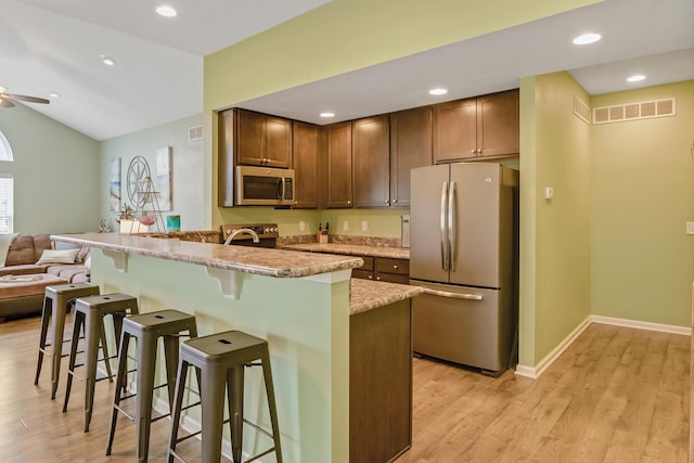 3242 Rossmore Cir, Powell, OH 43065 - kitchen featuring appliances with stainless steel finishes, open floor plan, a breakfast bar area, light wood-style flooring, and recessed lighting