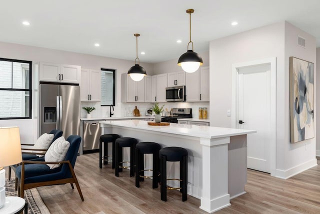 546 W Town St, Columbus, OH 43215 - kitchen featuring appliances with stainless steel finishes, light countertops, a center island, a breakfast bar, and backsplash