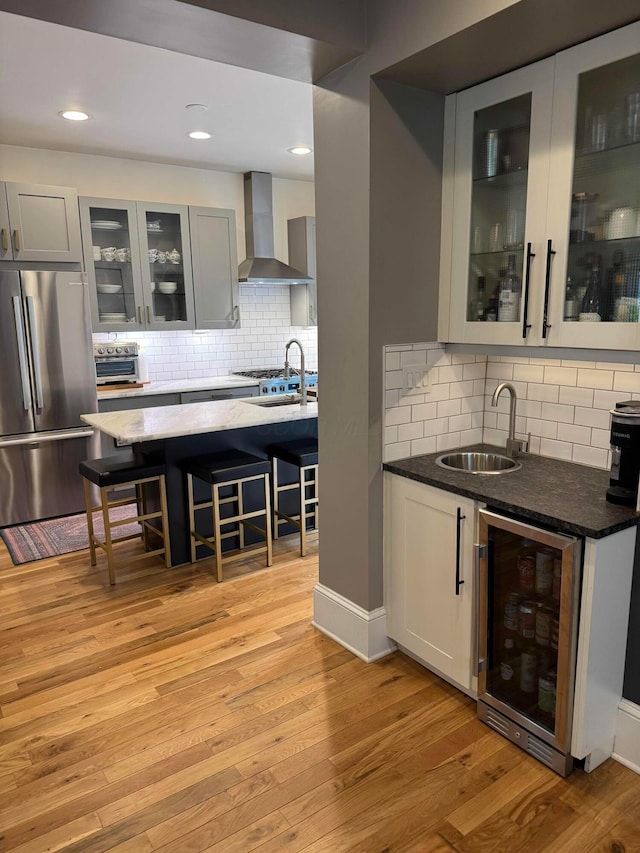 489 W 4th Ave, Columbus, OH 43201 - indoor wet bar featuring freestanding refrigerator, wine cooler, wall chimney range hood, tasteful backsplash, and light wood finished floors