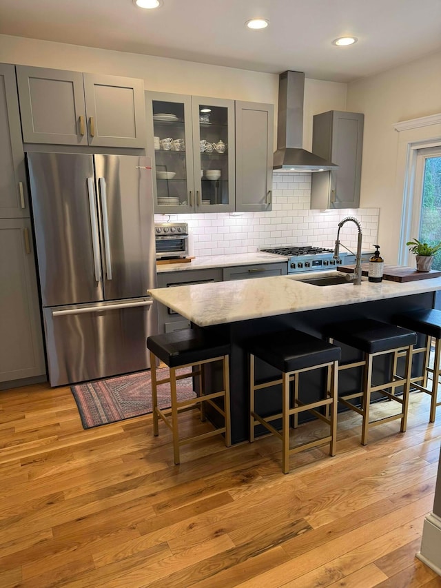 489 W 4th Ave, Columbus, OH 43201 - kitchen with freestanding refrigerator, wall chimney exhaust hood, gray cabinets, tasteful backsplash, and a breakfast bar