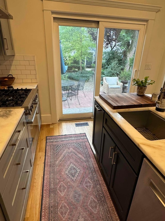 489 W 4th Ave, Columbus, OH 43201 - kitchen with light wood-type flooring, light countertops, tasteful backsplash, and under cabinet range hood