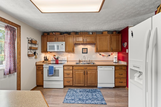 6492 Cherokee Rose Dr, Westerville, OH 43081 - kitchen with white appliances, light wood finished floors, a textured ceiling, and brown cabinetry