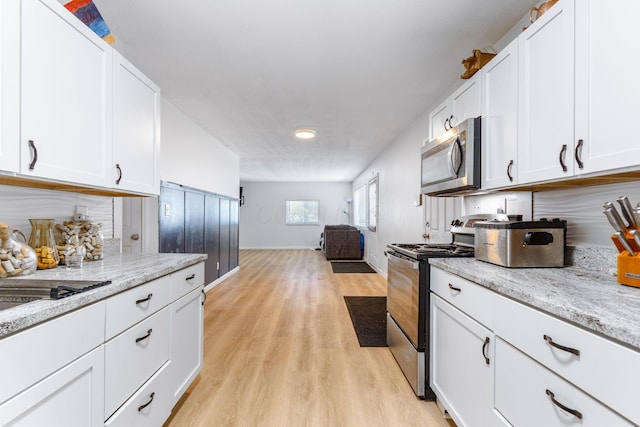 1894 Orlando Rd, Columbus, OH 43232 - kitchen with appliances with stainless steel finishes, light wood finished floors, open floor plan, white cabinetry, and light stone countertops