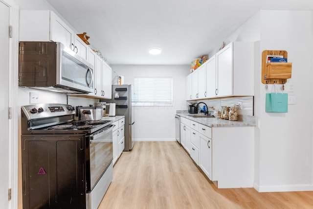 1894 Orlando Rd, Columbus, OH 43232 - kitchen with stainless steel appliances, light wood-type flooring, white cabinetry, and light stone counters