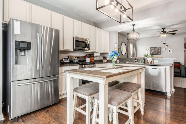 784 Brevard Cir, Pickerington, OH 43147 - kitchen featuring appliances with stainless steel finishes, a peninsula, dark wood-style flooring, white cabinetry, and pendant lighting