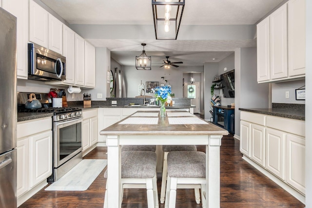 784 Brevard Cir, Pickerington, OH 43147 - kitchen featuring stainless steel appliances, dark wood-type flooring, a peninsula, a ceiling fan, and white cabinetry