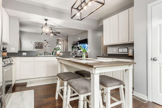 784 Brevard Cir, Pickerington, OH 43147 - kitchen with stainless steel gas range oven, a chandelier, white cabinetry, dark countertops, and dark wood finished floors